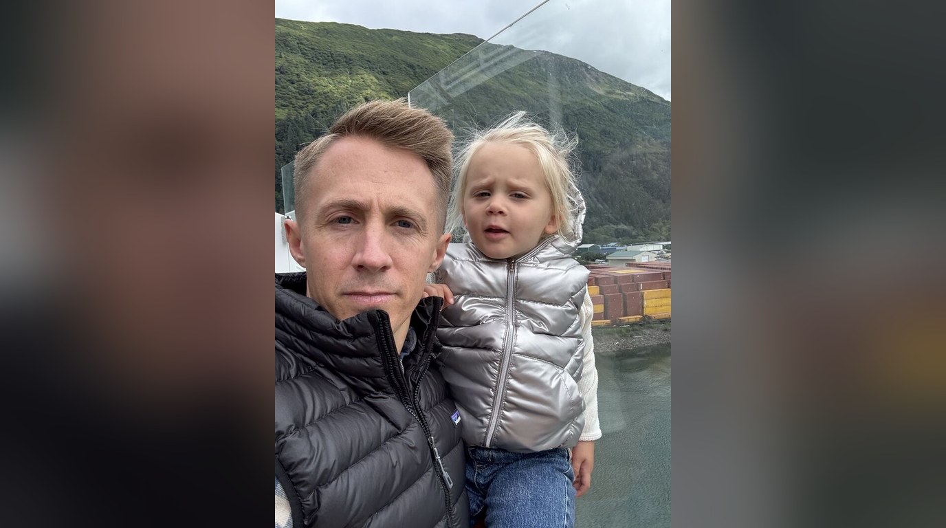 Selfie of Robert holding his daughter outdoors by the water